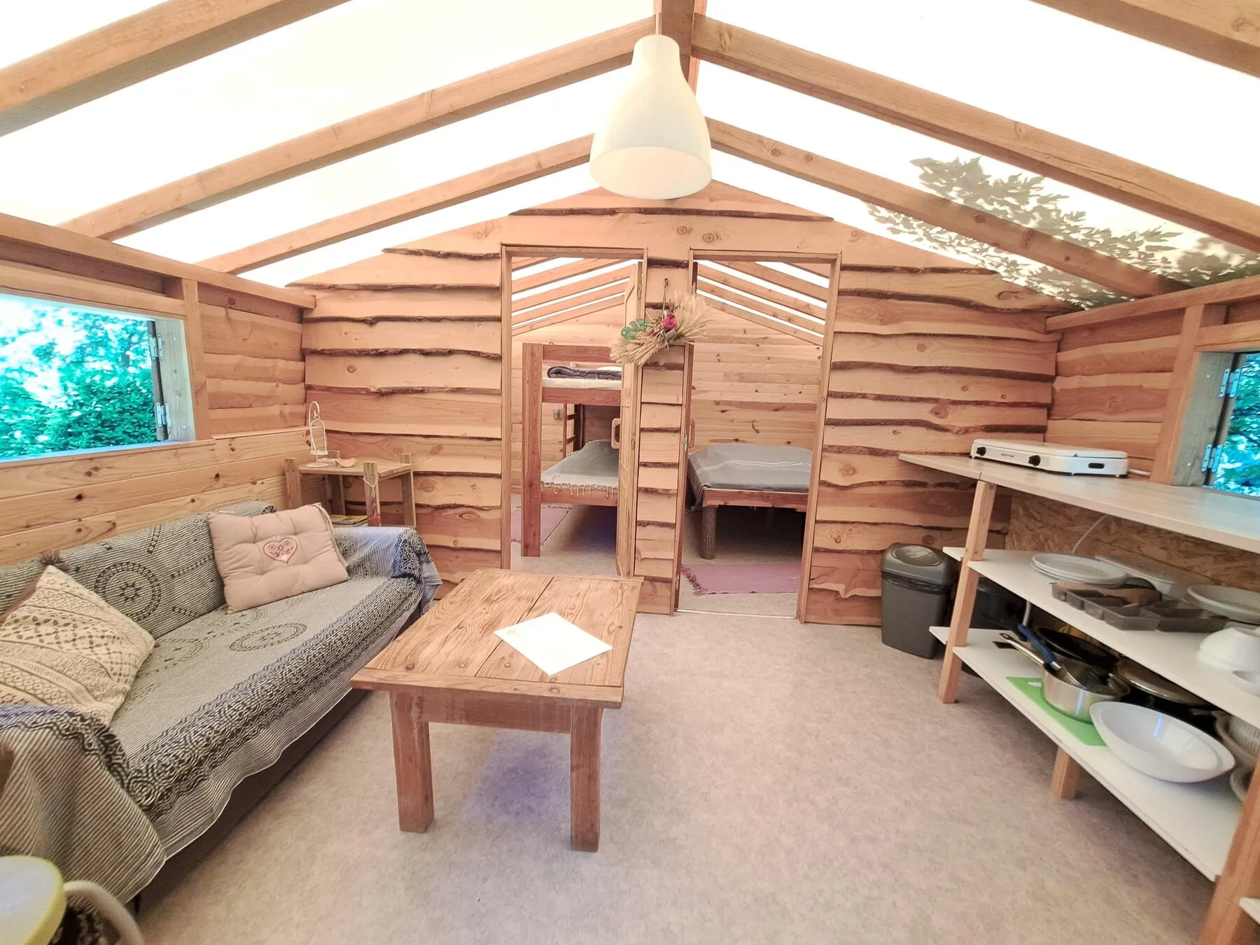 Der ganz aus Holz gefertigte Wohnraum der Trapperhütte, mit Sofa und Etagenbett