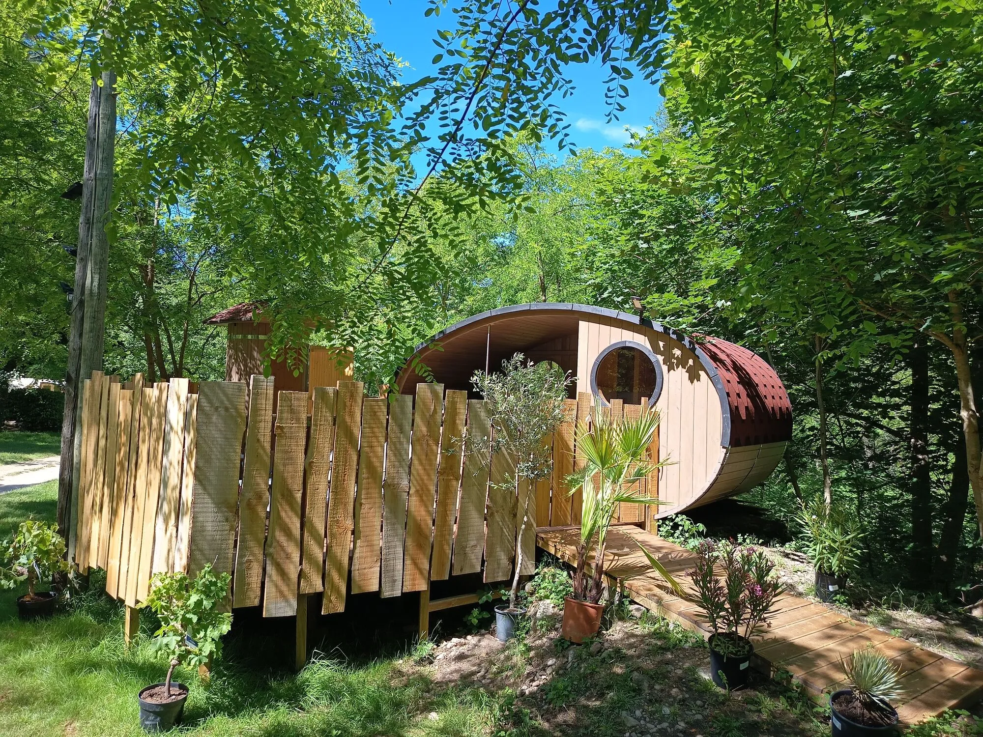 Die hölzerne Ellipse mit Whirlpool und Sauna, versteckt zwischen den Bäumen